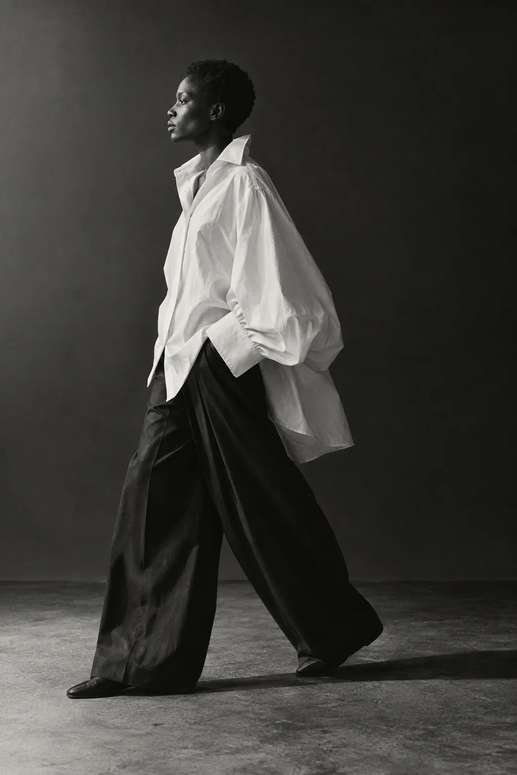 An oversized ivory shirt in motion over wide black trousers