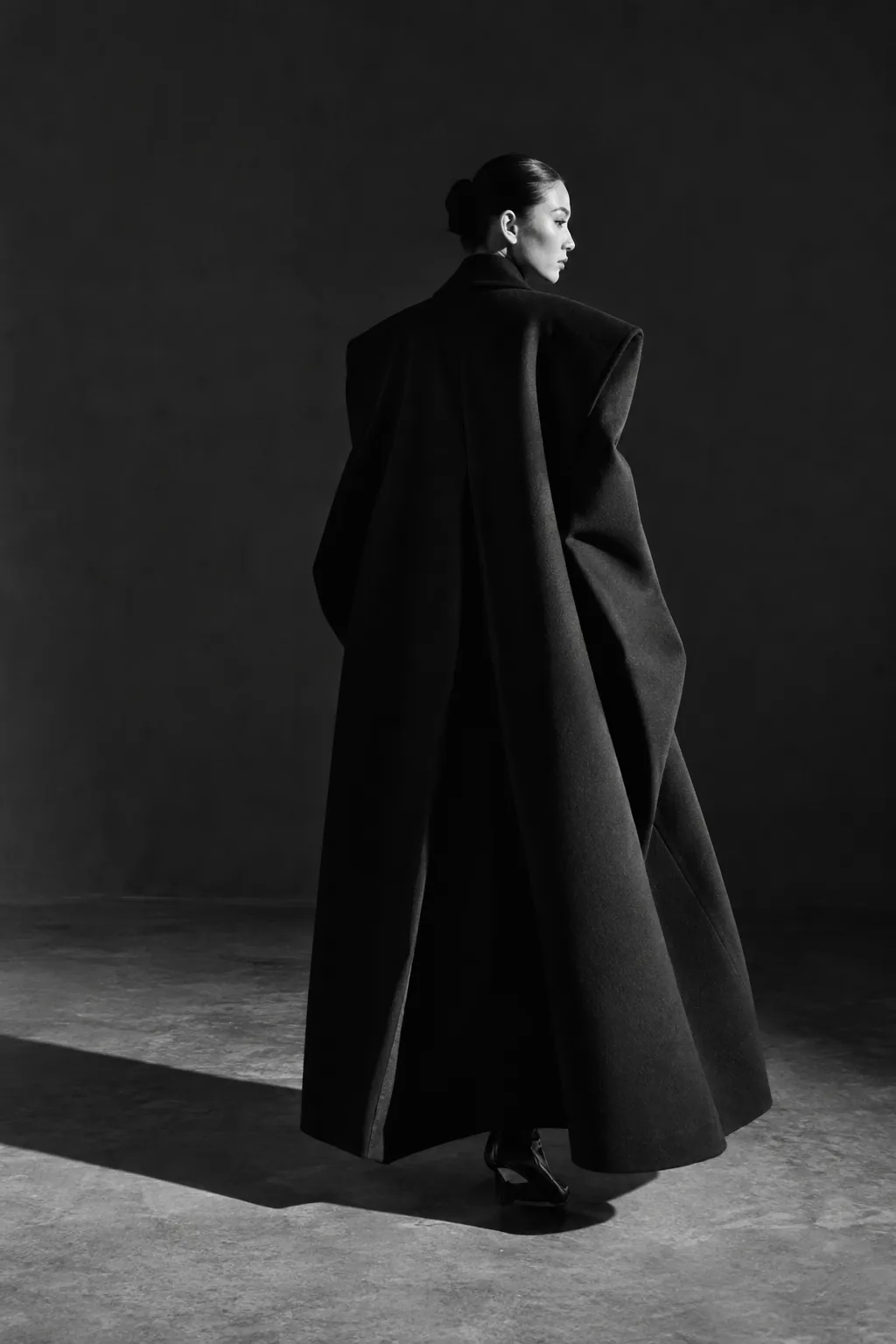 Back view of the long sculptural black cape coat